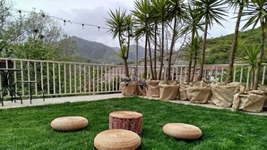 A grassy outdoor area with four woven stools, a metal fence, and palm trees. - Blue - Relaxation near Salerno, Pompeii &Amalfi (Pellezzano)