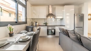 Een moderne keuken met witte kastjes, een ingebouwde oven en een roestvrijstalen koelkast.