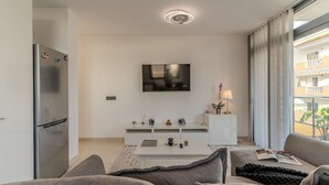 Een moderne woonkamer met een flatscreen televisie, een witte entertainmentkast en een bank.