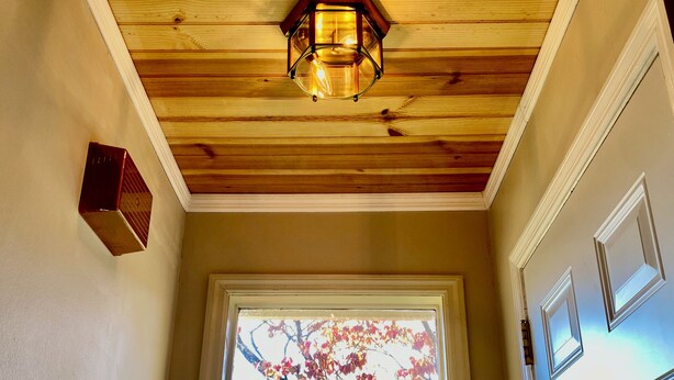 A hallway with a wooden ceiling, a wall-mounted thermostat, and a window with a view of trees. - Charming 2-bedroom Townhouse in Kennesaw with Single Floor Layout (Kennesaw)