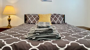 A neatly made bed with patterned bedding, a lamp, and a painting on the wall. - Charming 2-bedroom Townhouse in Kennesaw with Single Floor Layout (Kennesaw)
