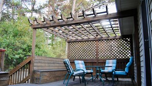 A wooden deck with a pergola, two blue chairs, and a small table. - Charming 2-bedroom Townhouse in Kennesaw with Single Floor Layout (Kennesaw)