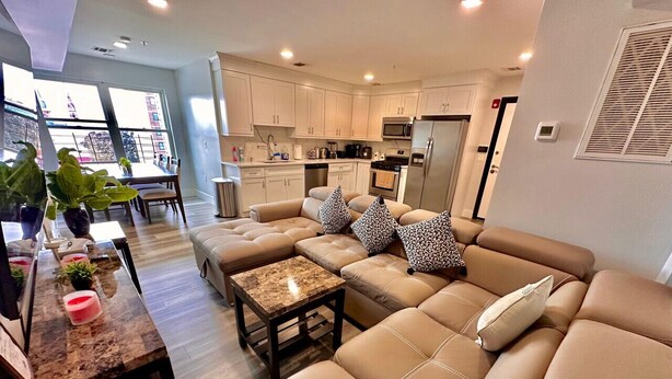 A modern living room with a sofa set, a coffee table, and a dining area with a table and chairs. - The Classy Suite: 2BR with Free Parking (Paterson)