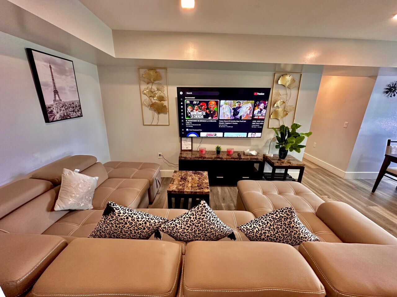 A living room with a sofa set, a flat-screen TV, and a decorative wall piece.