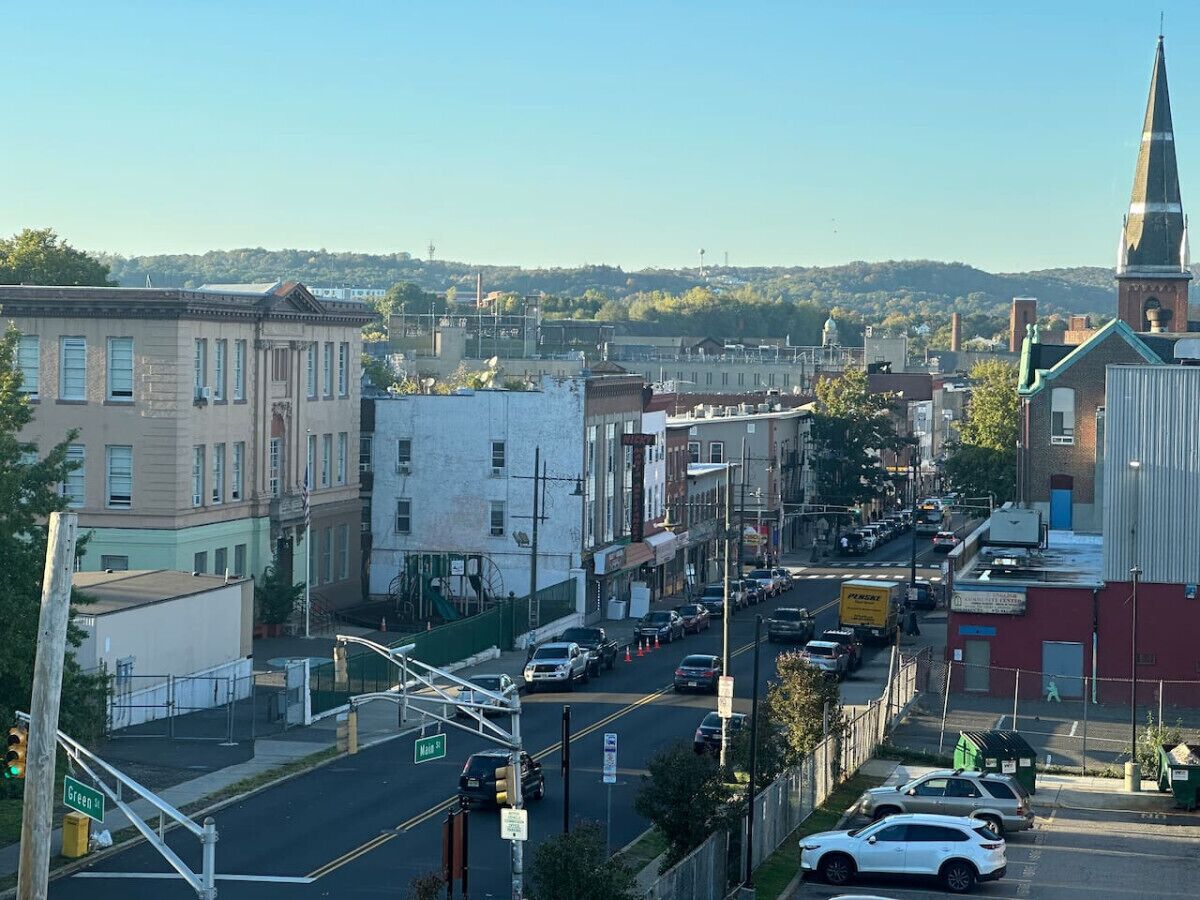 A street view of a town with buildings, a church steeple, and a clear sky.