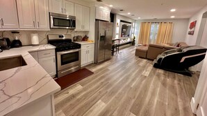 A modern kitchen with white cabinets, stainless steel appliances, and a wooden floor. - The Comfy Suite: 1BR with Free Parking (Paterson)