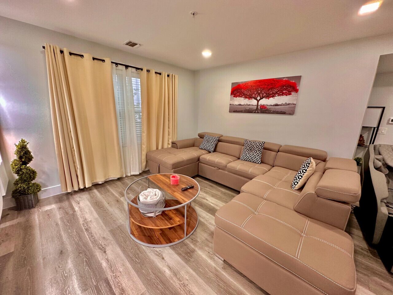 A modern living room with a sectional sofa, a round coffee table, and a potted plant.