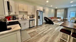 A modern kitchen with white cabinets, a stainless steel refrigerator, and a coffee maker. - The Stylish Spot: 1BR with Free Parking (Paterson)