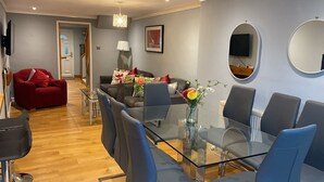 Ein modernes Wohnzimmer mit einem Glastisch, blauen Stühlen, einem roten Sofa und einem grauen Couchsofa.