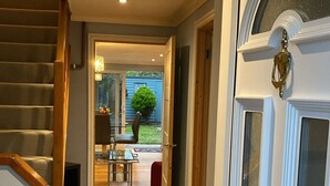 Ein Flur mit Holzboden, der zu einer Tür mit Messingklinke führt.
