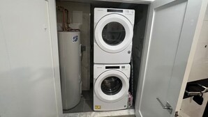 A compact laundry room with two stacked front-loading washing machines. - The Lovely Suite: 1BR close to NYC (Paterson)