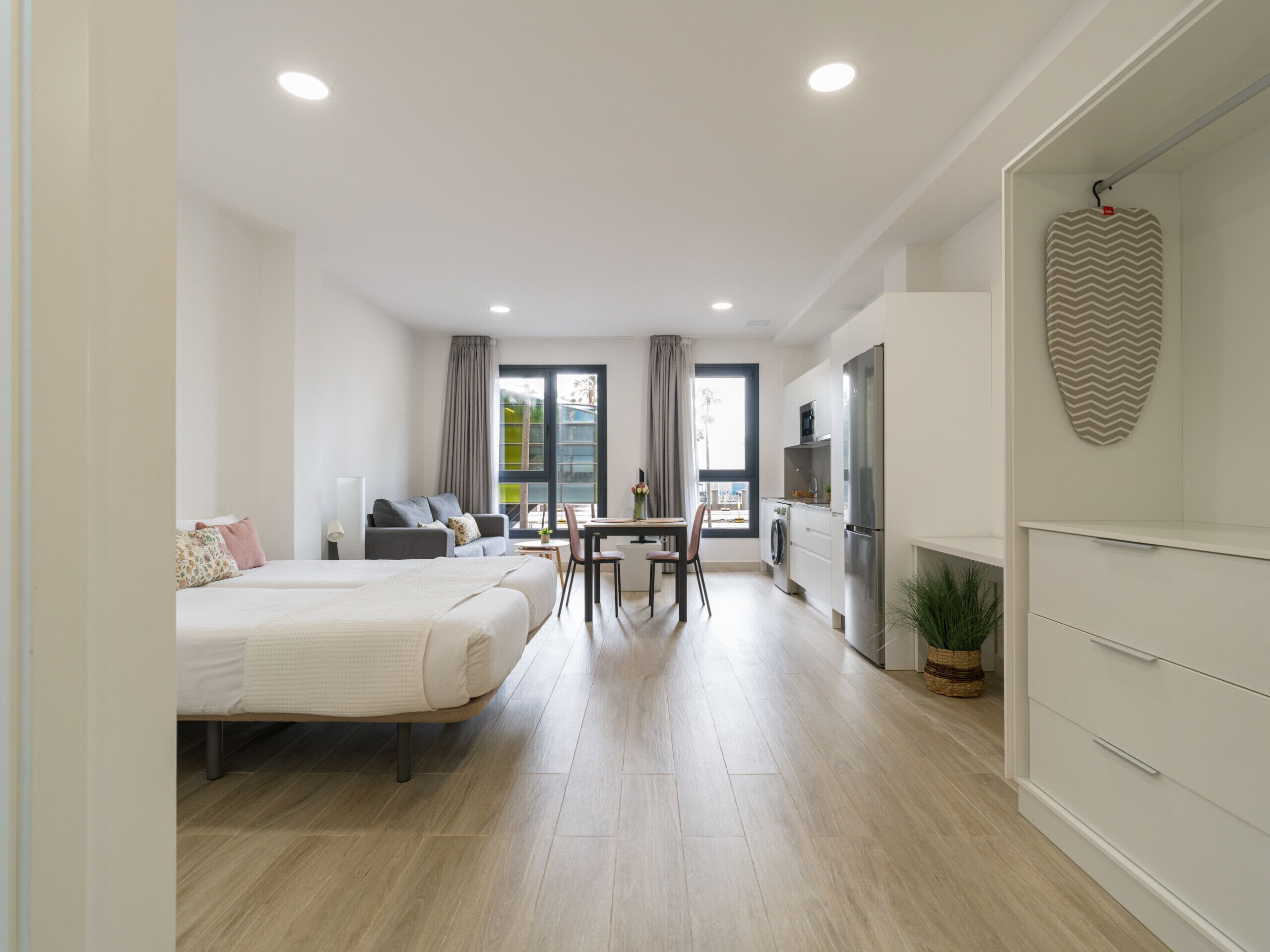 Et moderne hotelværelse med seng, skrivebord, stol, spisebord og et tekøkken.
