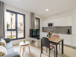 A modern apartment with a living area, a dining table, a kitchen, and large windows.