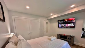 Ein Schlafzimmer mit einem großen Bett, einem an der Wand befestigten Fernseher und einem Holzschrank.