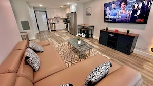 Ein modernes Wohnzimmer mit einer Couch, einem Couchtisch und einem Fernseher, der einen Filmplakat zeigt.
