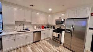 Una cocina moderna con armarios blancos, electrodomésticos de acero inoxidable y suelo de madera.