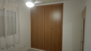 A room with a wooden wardrobe, a ceiling light, and a window with sheer curtains. - Detached Villa with Communal Pool Close to beaches and Golf Course. (Mazarron)