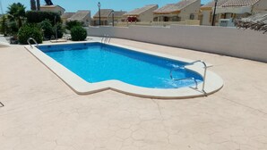 A rectangular swimming pool with a hexagonal tiled deck, surrounded by a low wall and a few plants. - Detached Villa with Communal Pool Close to beaches and Golf Course. (Mazarron)