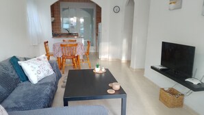 A living room with a sofa, a coffee table, a TV, and a dining area with chairs and a table. - Detached Villa with Communal Pool Close to beaches and Golf Course. (Mazarron)