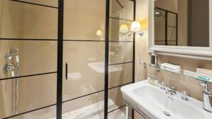 Een moderne badkamer met een douchecabine van glas, een witte wastafel met spiegel en een handdoekhouder.