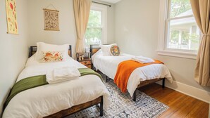 A bedroom with two beds, a patterned rug, a ceiling fan, and a window with curtains. - Charming 2-bedroom house with WiFi, AC in brilliant Geneva (Geneva)