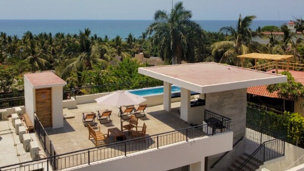 Una terraza en la azotea con piscina, mobiliario exterior y vistas al océano.