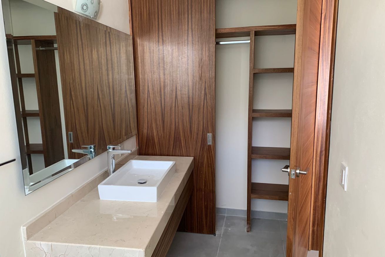 A bathroom with a white sink, a mirror, and wooden shelving.