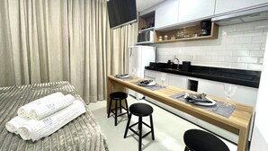 A compact hotel room with a bed, a small kitchenette, and a dining area. - RN Studio Premium 103 - Vista Mar (Maceió)