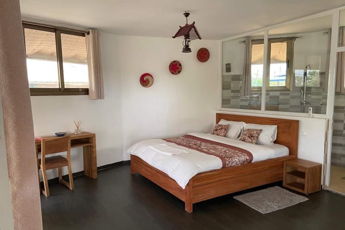 A bedroom with a wooden bed, a desk, and a window.