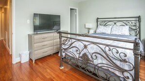 A bedroom with a metal bed frame, a television on a dresser, and a mirror on the wall. - Cozy 3 Bedroom/Great Location (Arlington)