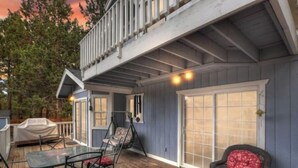 Un patio couvert avec une table et des chaises, un fauteuil suspendu et un espace barbecue abrité.