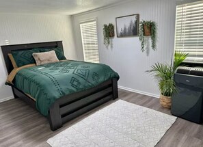 Cozy retreat with a dark bed frame, green bedspread, and two potted plants.