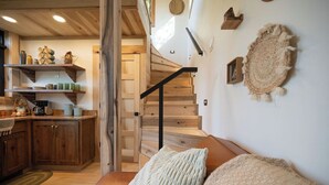 Een gezellig interieur met een houten trap, een keuken met houten planken en een comfortabele bruine leren bank.