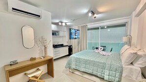 A modern hotel room with a bed, bedside table, and a small desk with a chair. - RN Studio Premium 412 - Frente Mar (Maceió)
