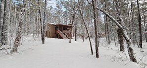 A cabin in a snowy forest with a wooden staircase leading to a deck. - Northwoods (#8) Cabin in the Pines (Pinetop-Lakeside)