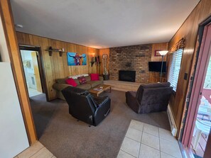 A living room with a sofa, chairs, a coffee table, a fireplace, and a television.