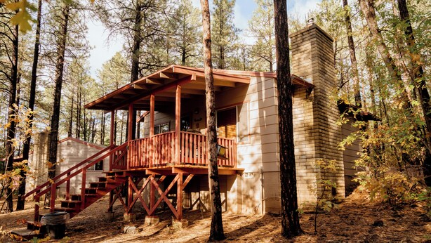 A cabin with a wooden deck and stairs, surrounded by trees. - Northwoods (#9) Cabin in the Pines (Pinetop-Lakeside)