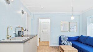Eine moderne Küche mit Spüle und Kaffeemaschine, ein blaues Sofa und ein Holztisch.