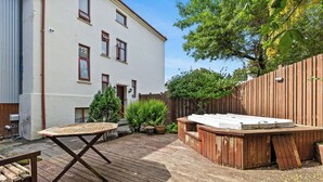Eine Holzterrasse mit Whirlpool, Tisch und Bank.
