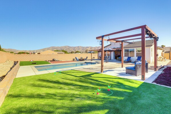 Um quintal com piscina, pérgola e área de varanda.