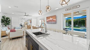 A modern kitchen with a large island, a dining area, and a view of a pool.