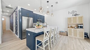 A modern kitchen with a central island, stainless steel appliances, and a 'hello coffee' sign.