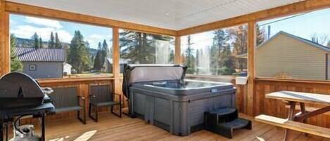 Terraza techada al aire libre con jacuzzi, parrilla y zona de estar.