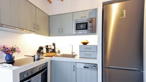 Una cuina moderna amb armaris grisos, un frigorífic d'acer inoxidable, un microones, un forn i un rentaplats.