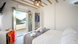 Un dormitori amb llit, escriptori i vista al mar.