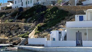 Edifici a la costa amb diversos balcons, una escalinata de pedra i una barca fondejada a prop.