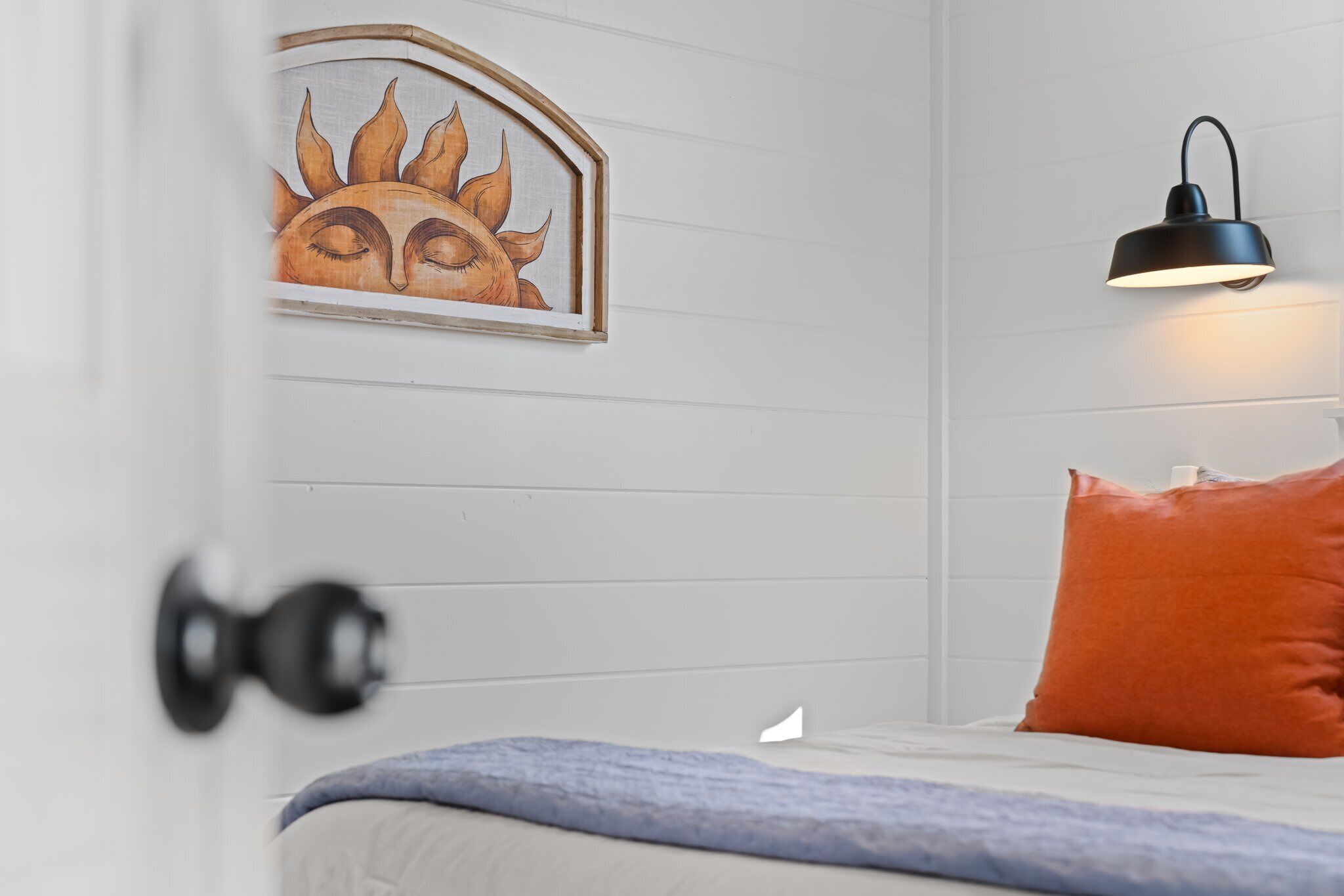 Ein Schlafzimmer mit einem Bett, einer Wandleuchte und einem gerahmten Kunstwerk.