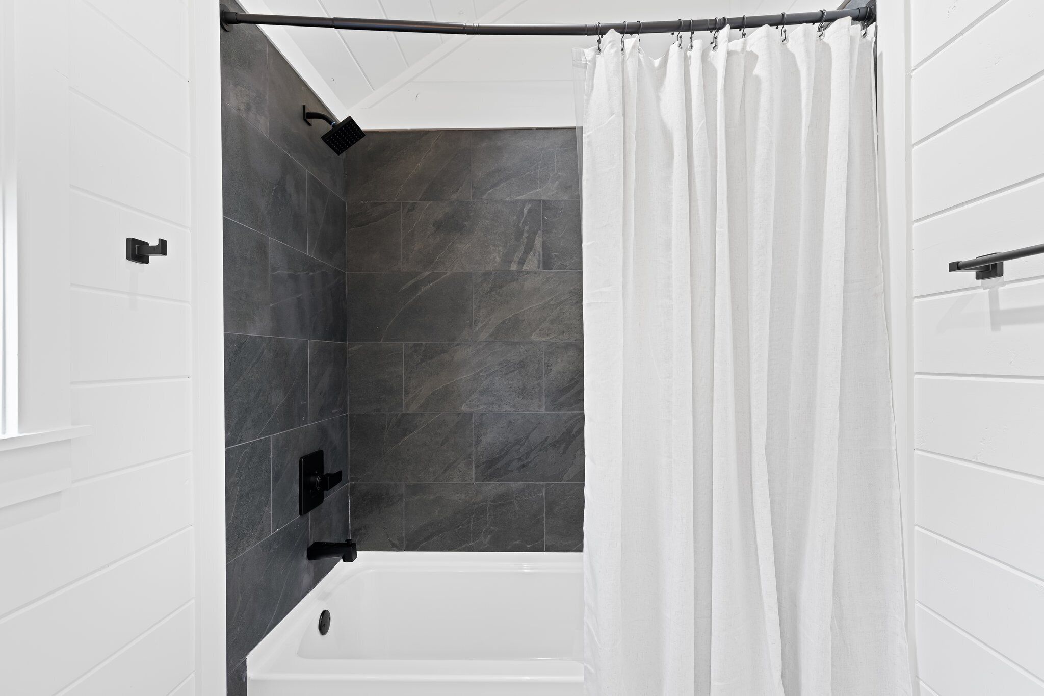 Un bagno moderno con una vasca, una zona doccia e un tendaggio bianco.