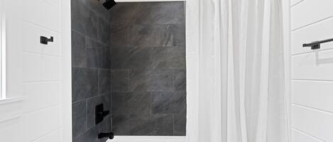 Une salle de bain moderne avec une baignoire, un espace douche et un rideau blanc.