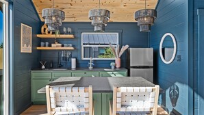 Une cuisine moderne avec des meubles de couleur verte, un îlot central et des luminaires suspendus.